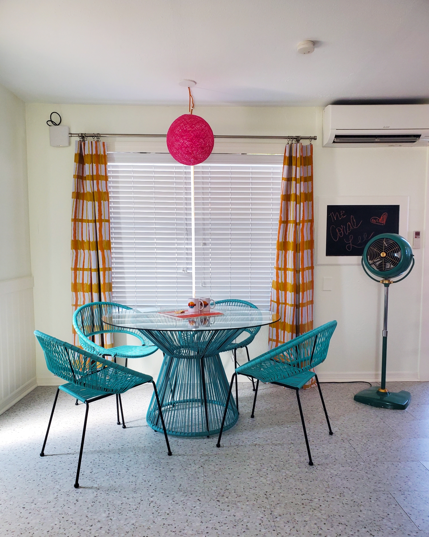 The Coral Lee dining table, chairs, bright patterned curtains and hot pink globe chandelier.