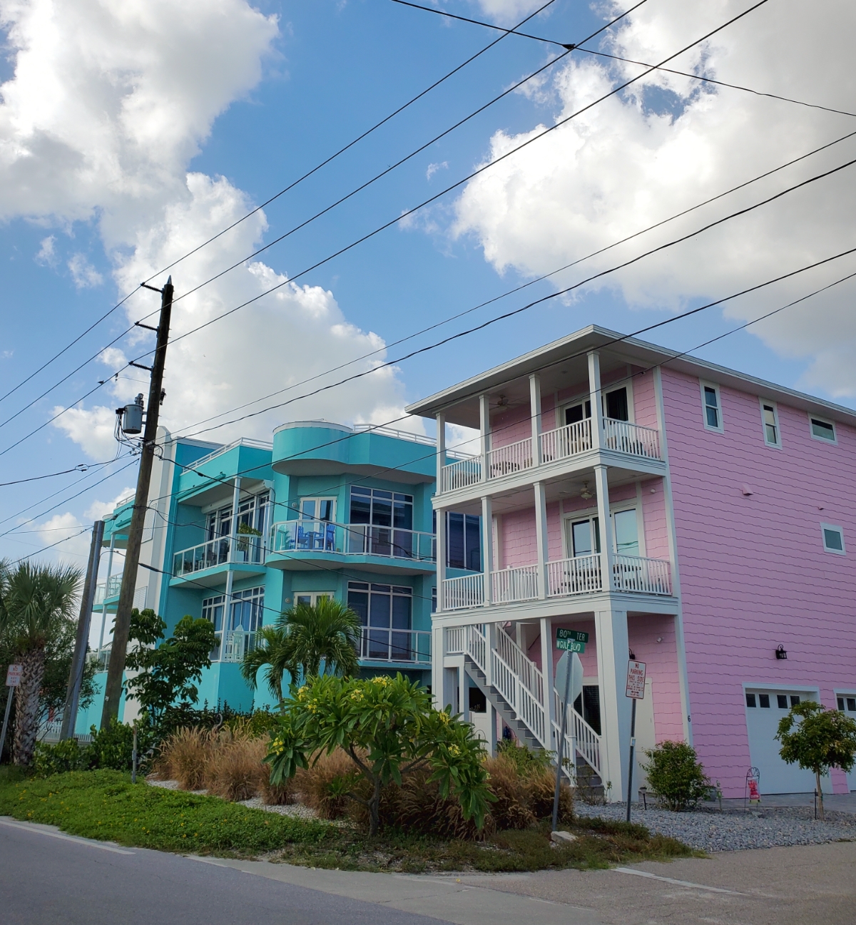 Two contemporary homes side by side in Sunset Beach. One is aqua and one is pink.