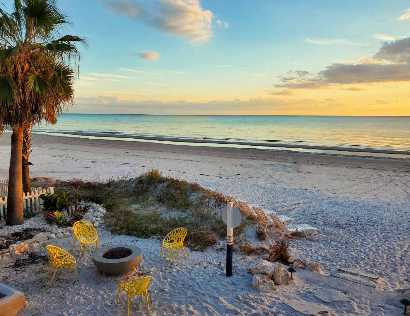 Sunburst Inn view of the beach, the Gulf of Mexico, with the modern yellow chairs and fire pit in the foreground